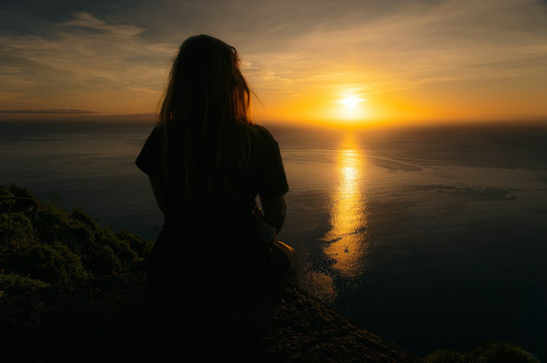 person meditating at sunrise